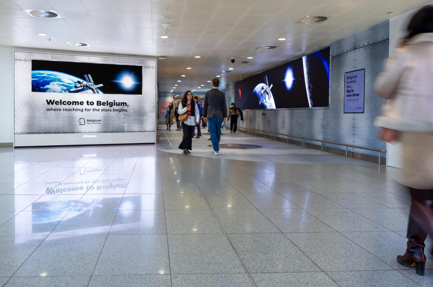 Campagne OOH créative avec un tunnel expérientiel lumineux et immersif pour la chancellerie du premier ministre, visible à Brussels Airport du 19 décembre 2025 au 16 janvier 2026