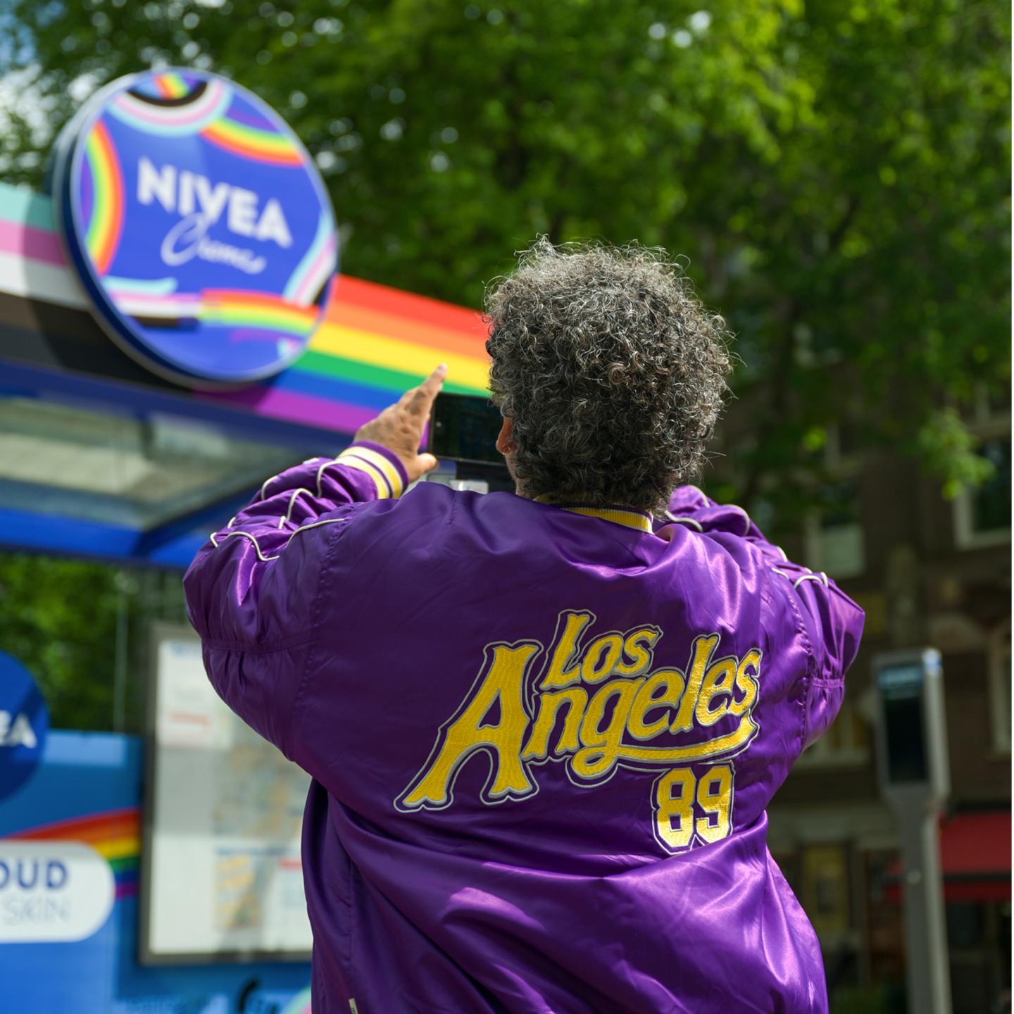 A man photographing a 3D Nivea advertisement on a JCDecaux bus shelter in Amsterdam