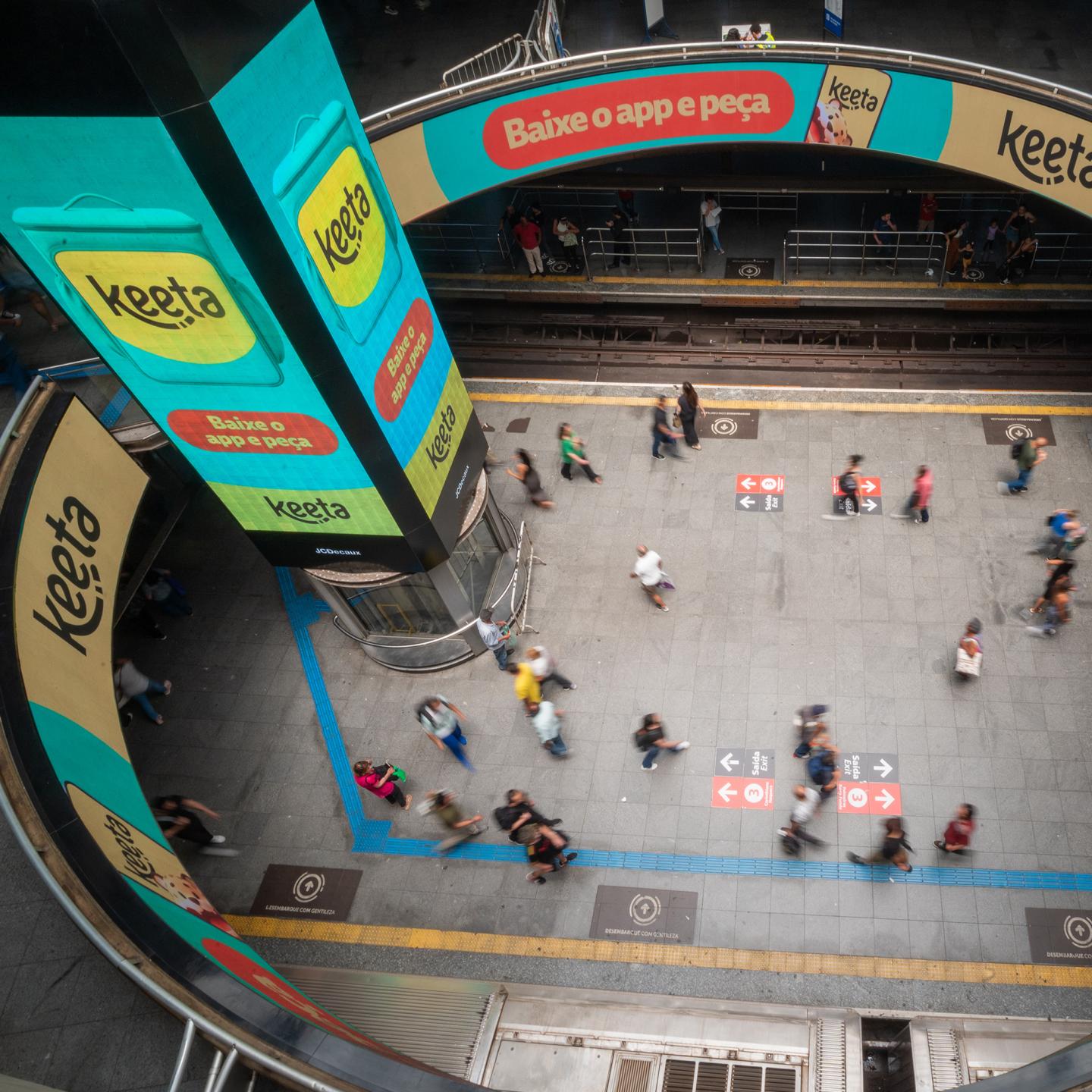 Commuters in São Paulo passing by JCDecaux displays advertising the new Keeta delivery app.
