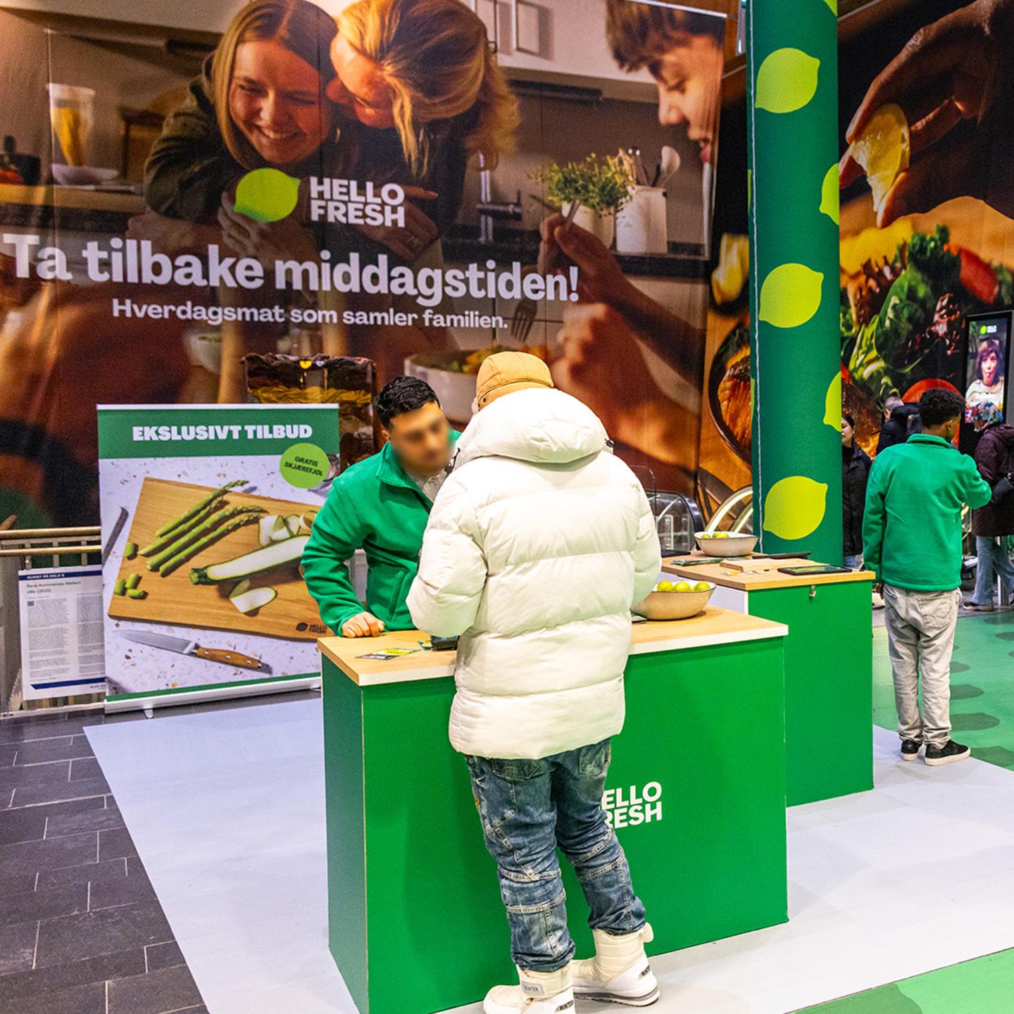 Commuters discovering the HelloFresh campaign by JCDecaux at Oslo Central Station, stopping to look at the bright green visuals as they move through the escalator area.