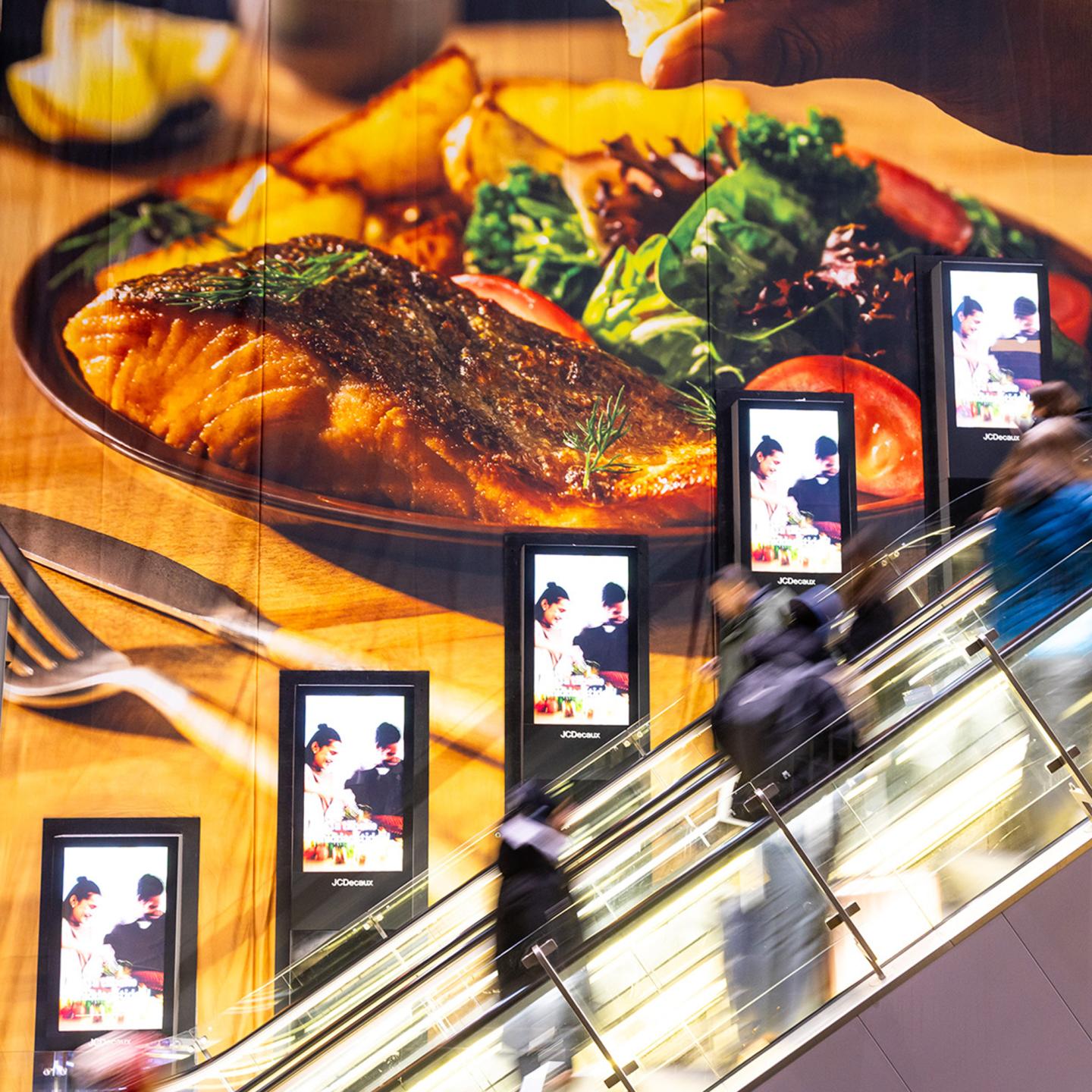 - HelloFresh branding displayed on JCDecaux floor and escalator media in Oslo Central Station, with bright green visuals guiding commuters along their journey.