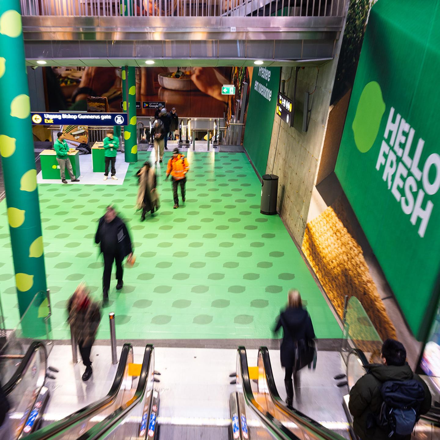 HelloFresh food advertising with JCDecaux along the escalators in Oslo Central Station, featuring colourful meal visuals as commuters travel up and down.