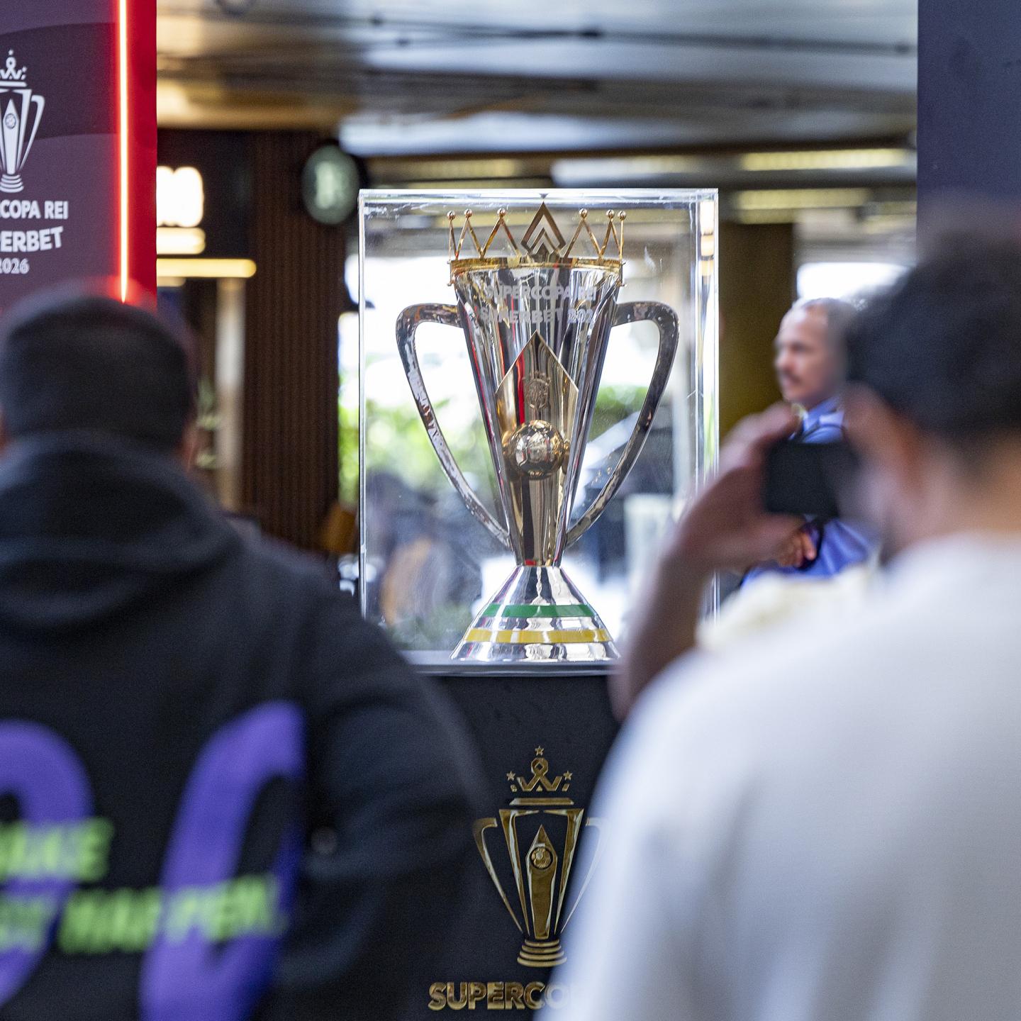 Wide view of Brasilia airport arrivals hall featuring a Supercopa Rei trophy activation in the middle of the passenger flow