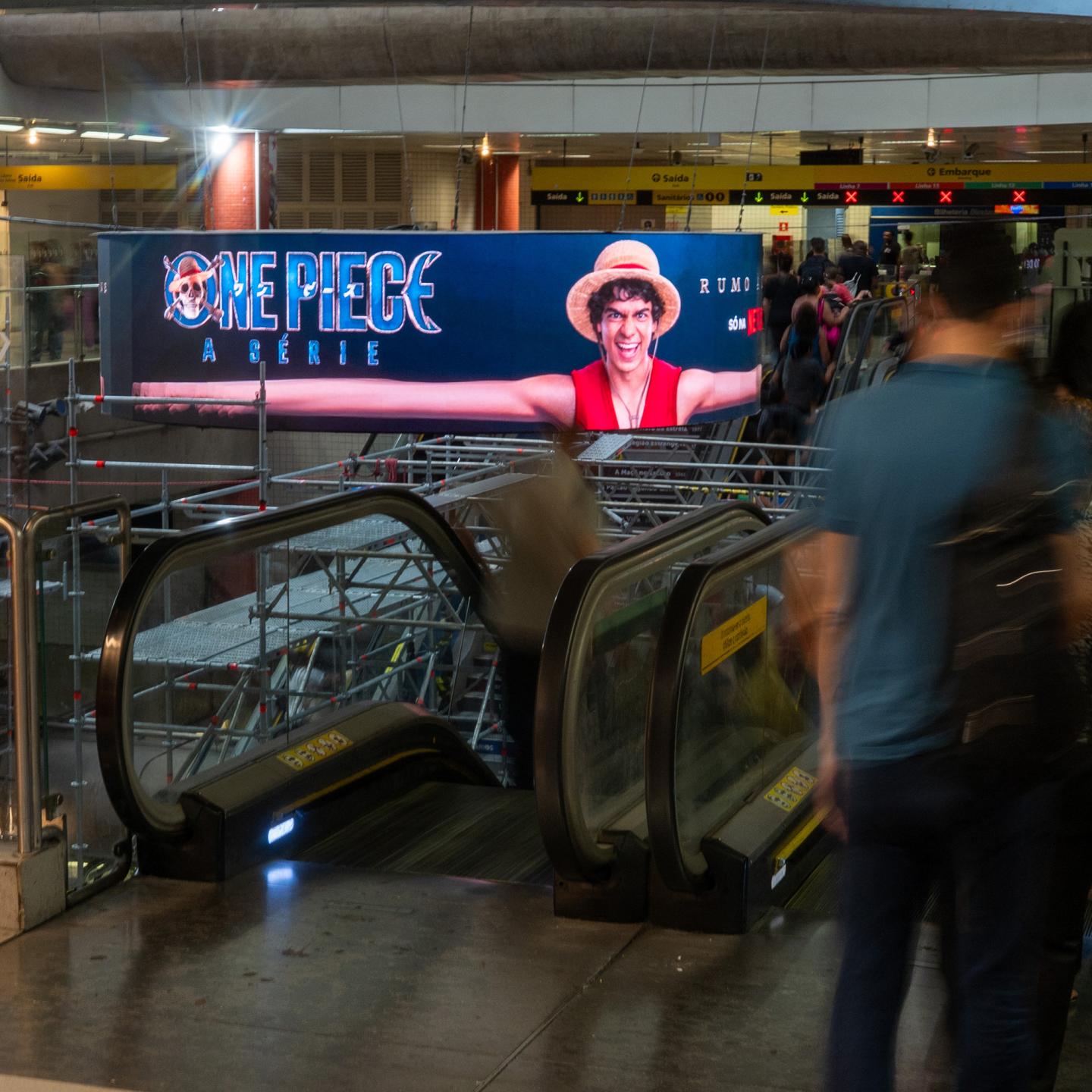 Close-up of Luffy’s elastic arms surrounding a circular digital screen promoting One Piece Season 2 in the São Paulo underground.