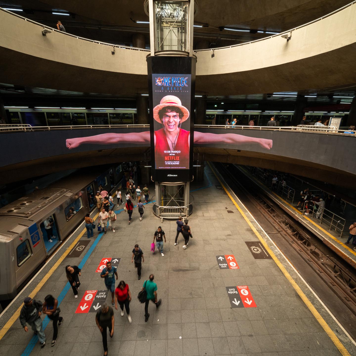 Immersive One Piece Season 2 street furniture campaign in São Paulo metro, featuring Luffy’s elastic arms wrapped around a circular digital screen.