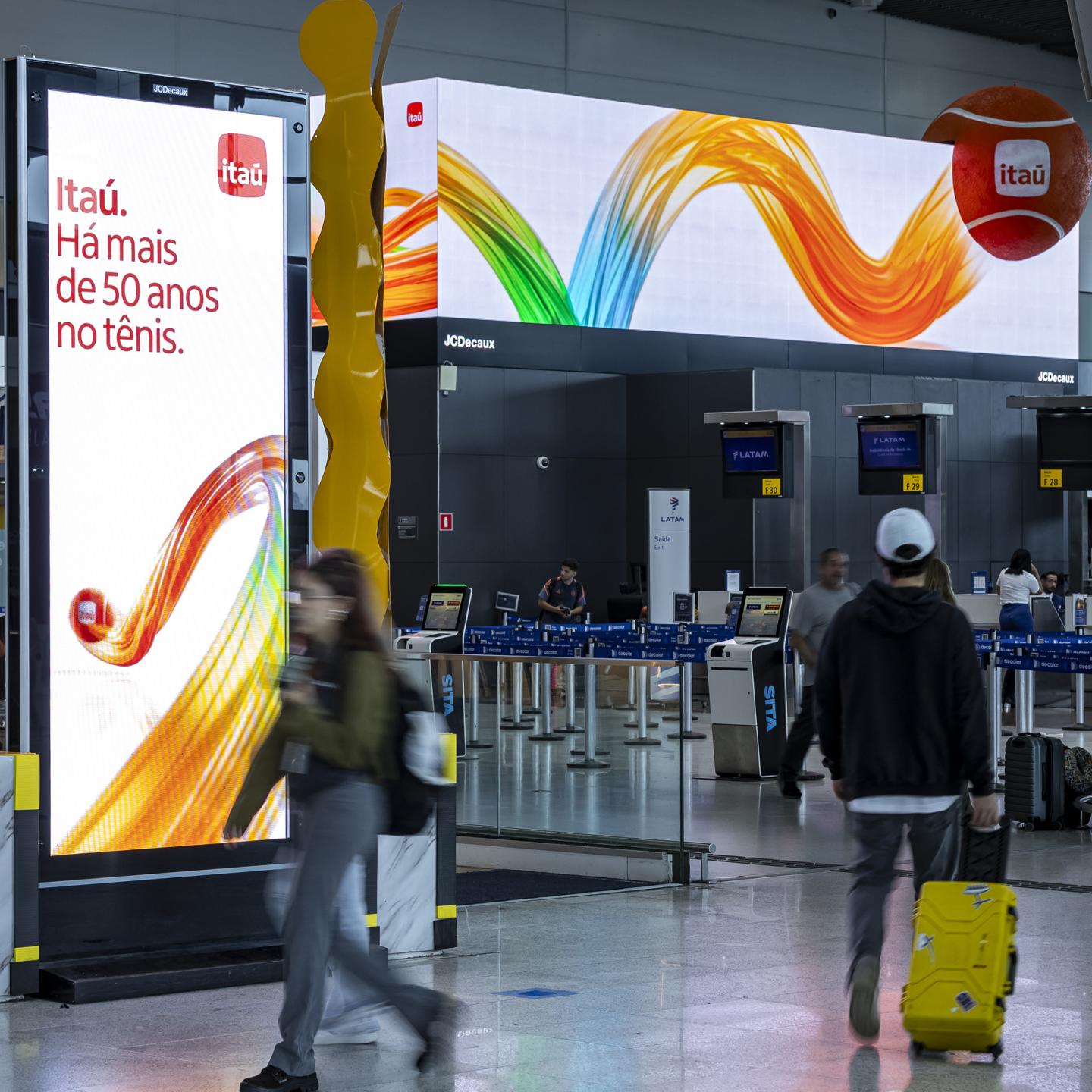Travellers walking through a departure hall immersed in Miami Open visuals created by JCDecaux for Itaú