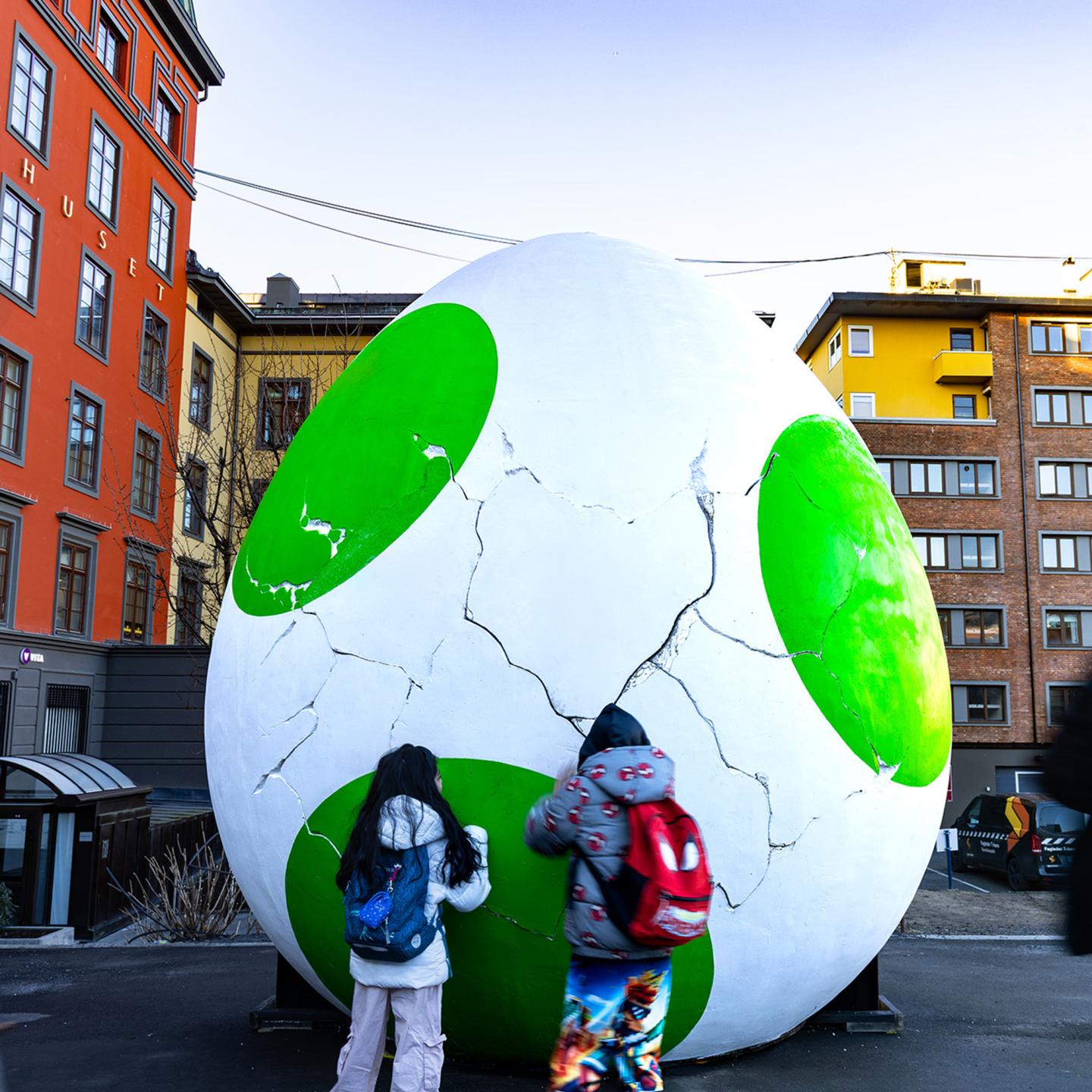 A JCDecaux special build in Norway showing a large Yoshi egg integrated with digital screens displaying movie posters for Super Mario Galaxy amidst a snowy urban landscape