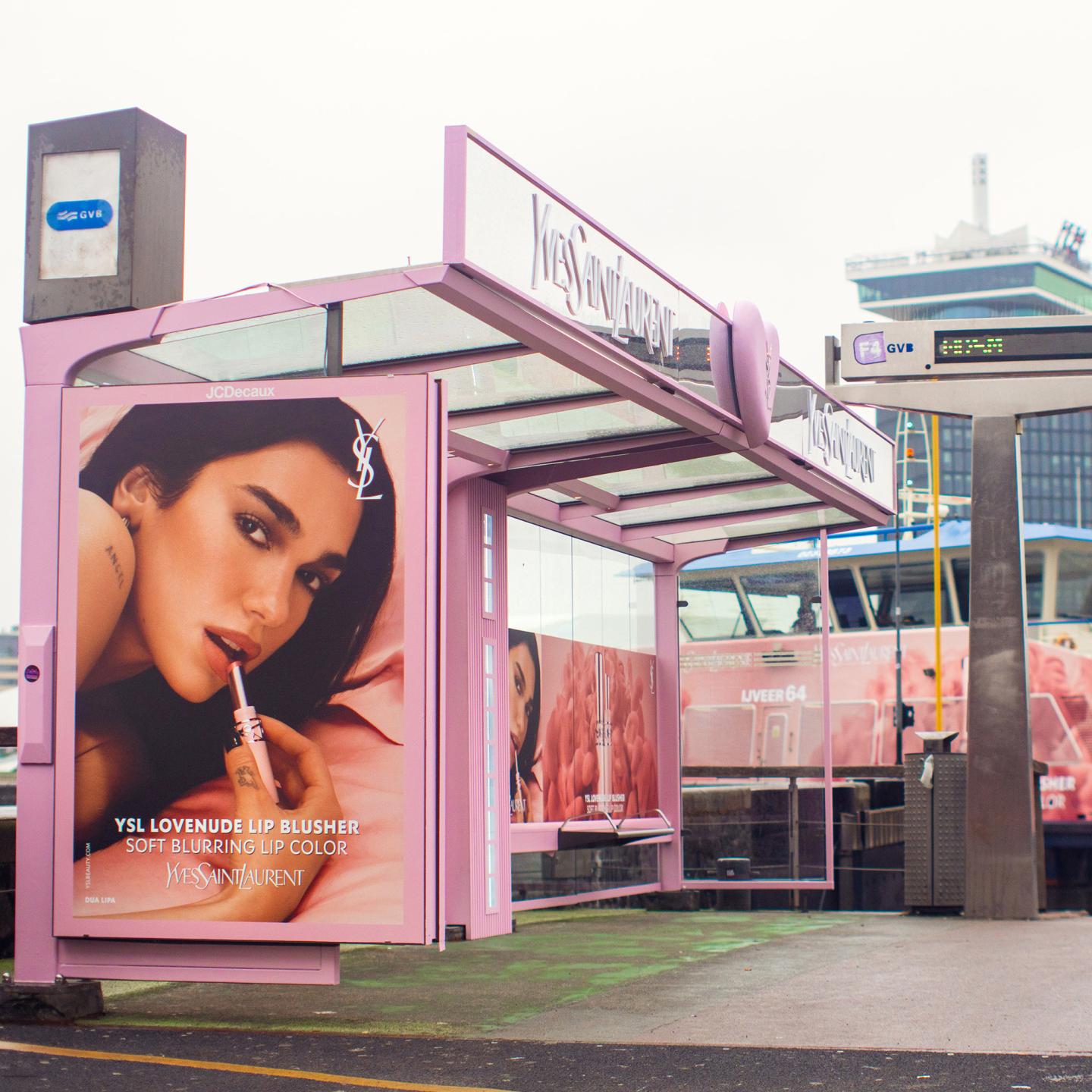 Close-up of a high-impact advertising poster featuring Dua Lipa for the YSL Lovenude fragrance, displayed in an urban setting.