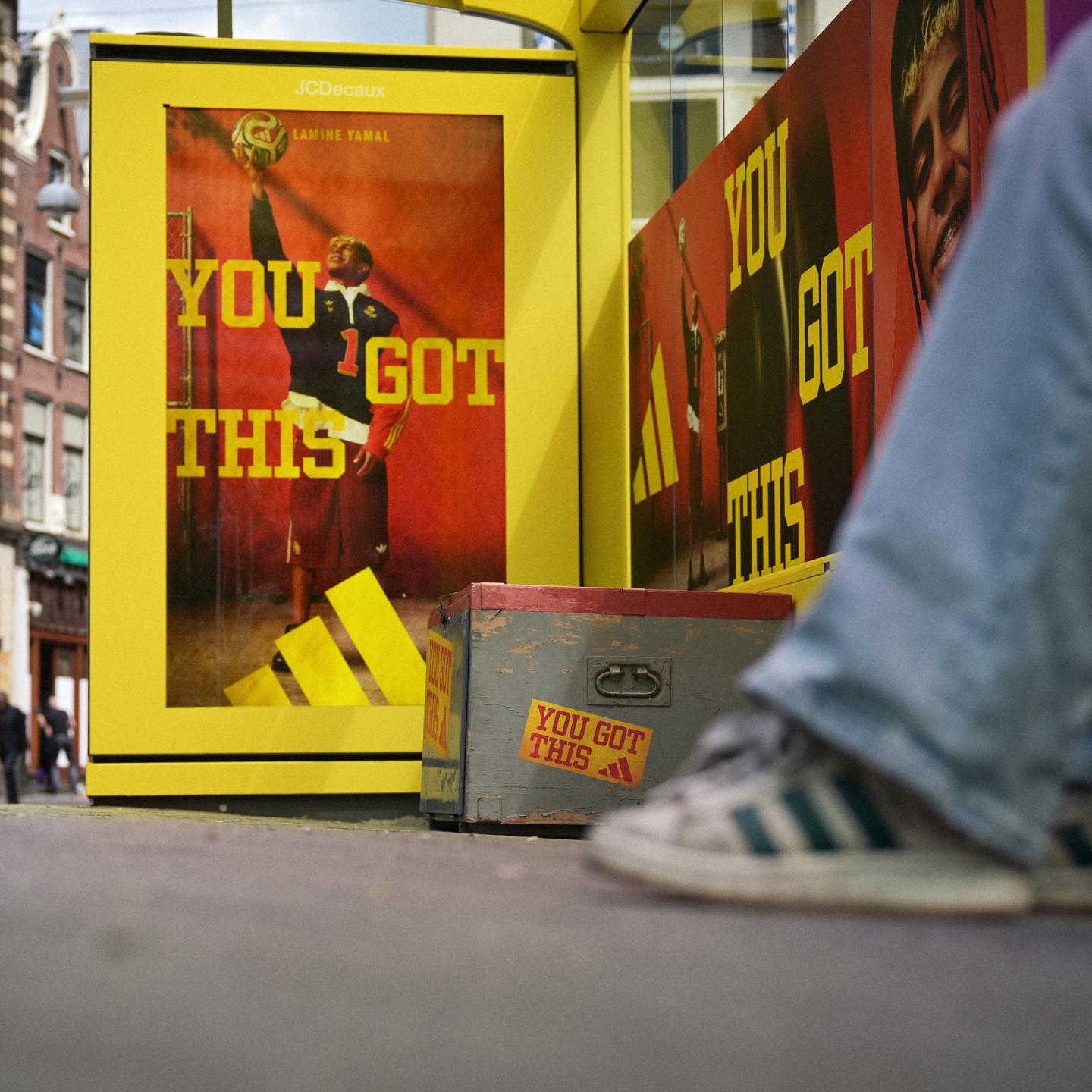 World Cup-themed JCDecaux bus shelter in Amsterdam featuring adidas branding, sports equipment crates and a large 3D Trionda football above the structure.