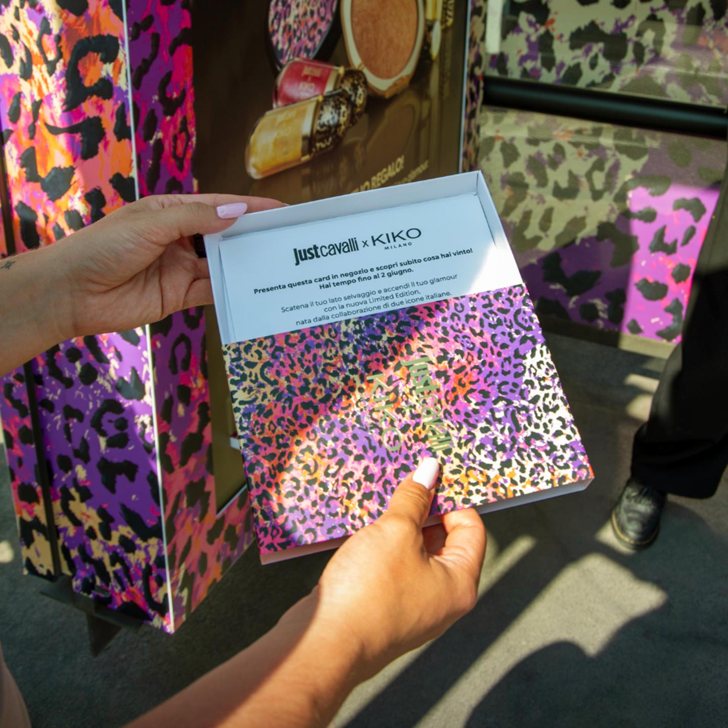 Hand holding a leopard-print KIKO Milano box containing a promotional Just Cavalli x KIKO Milano card