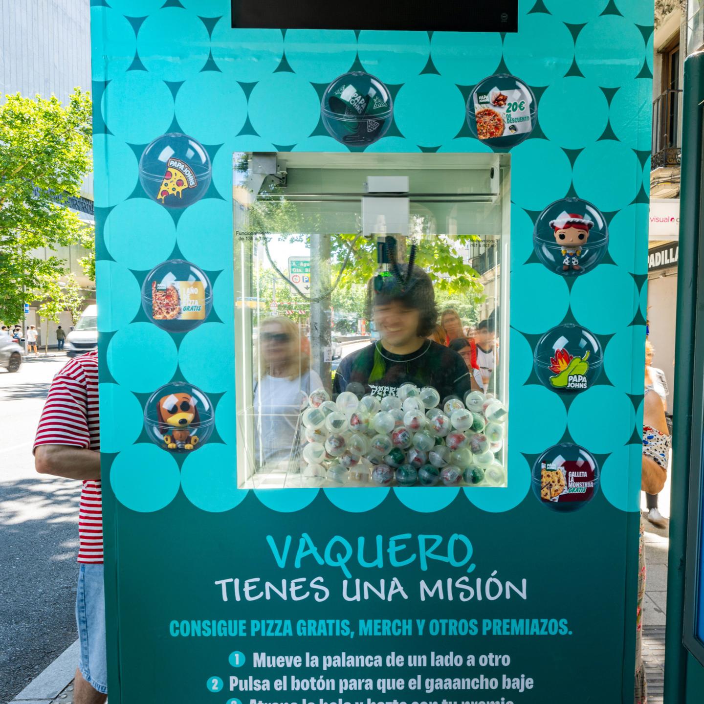 JCDecaux bus shelter dressed in Toy Story 5 artwork in central Madrid, with colourful characters and a Papa Johns-branded activation attracting pedestrians.