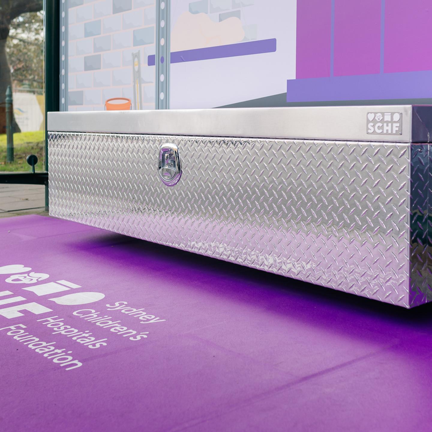 Row of bright purple lockers installed beneath illustrated sports jerseys at a Sydney bus stop.