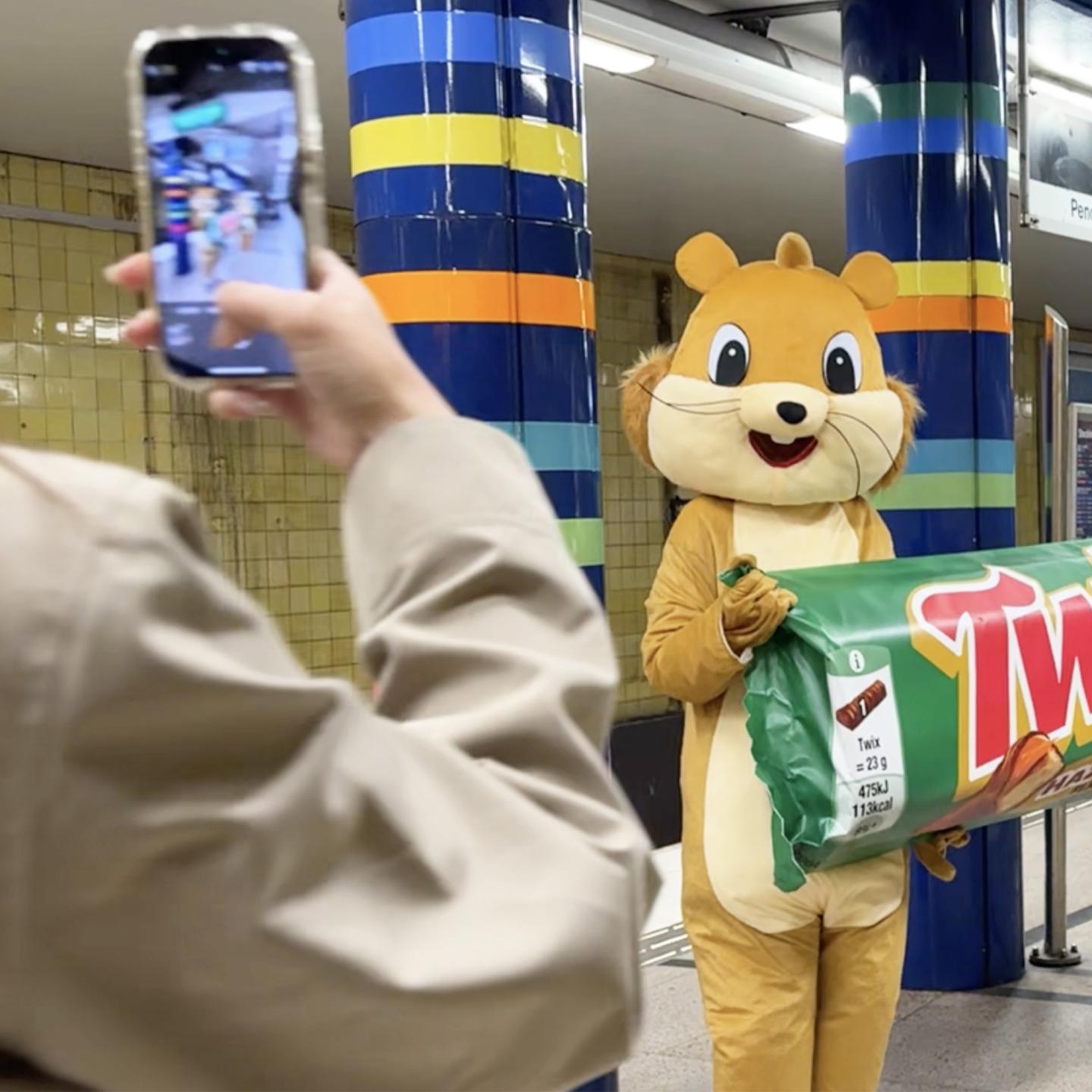 JCDecaux squirrel characters presenting an oversized Twix Hazelnut bar inside the Stockholm metro, engaging commuters and onlookers.