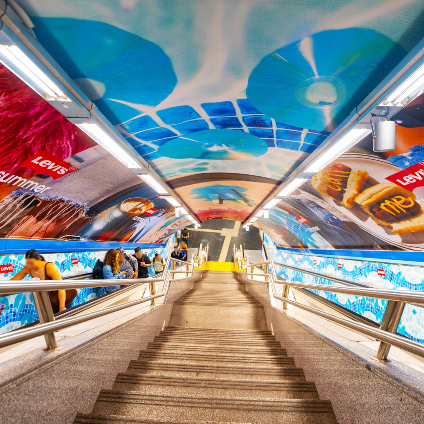 Escalators at Tribunal station in Madrid covered in Levi’s summer visuals and denim graphics, part of a JCDecaux immersive metro campaign.