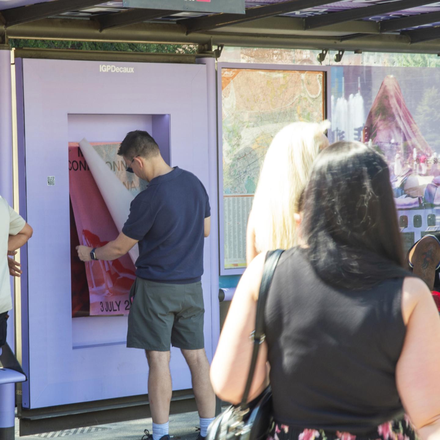 A fan peeling off a free Madonna Confessions II promotional poster from the interactive street furniture dispenser in Milan