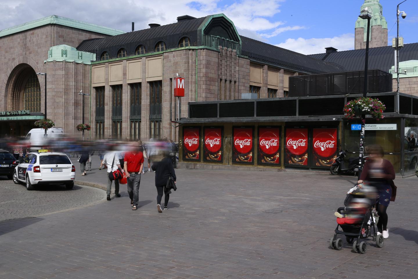 Monta coca cola ulkomainosta rivissä logo korkissa