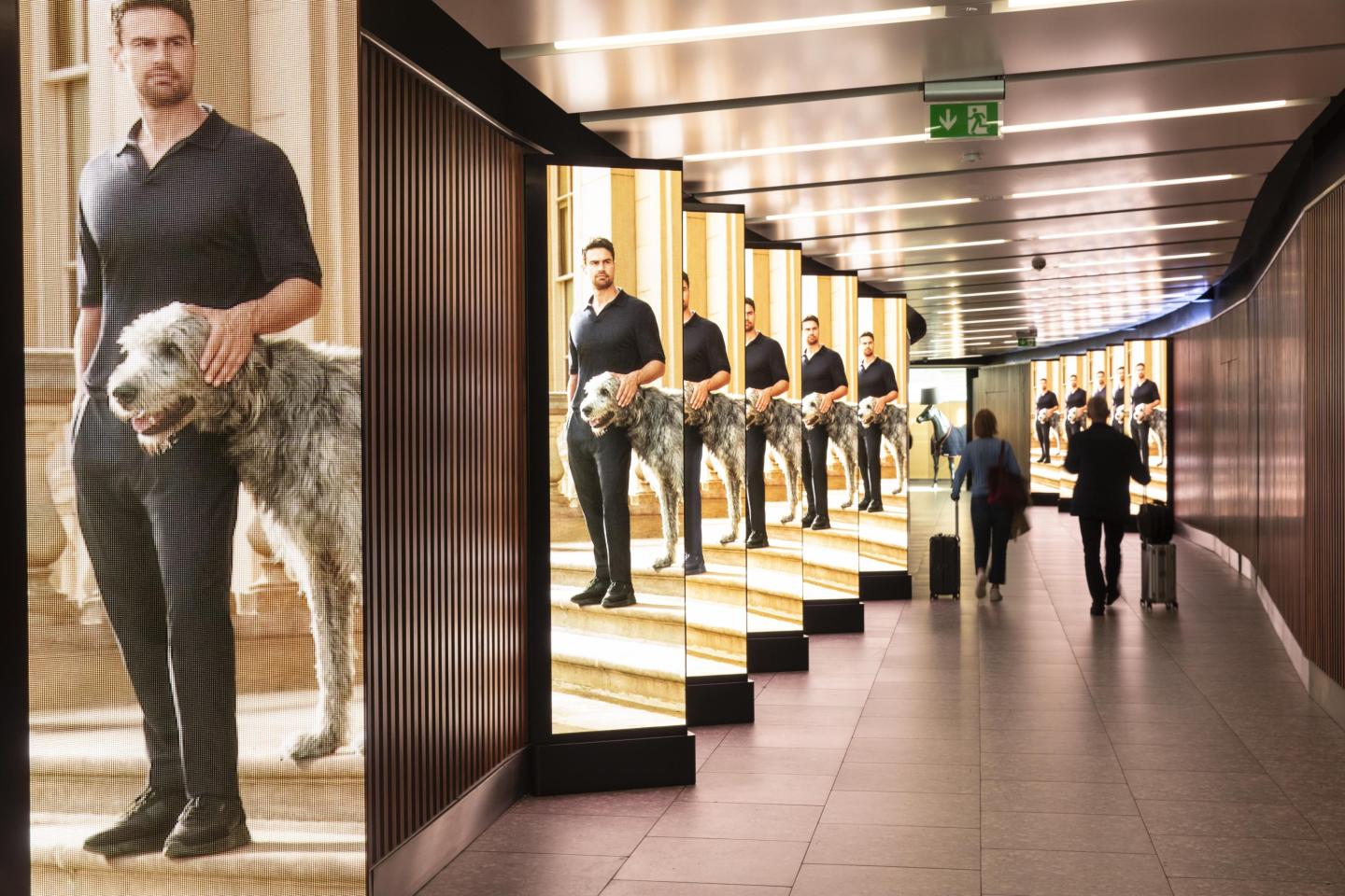 A row of JCDecaux digital Out-of-Home advertising screens in a corridor