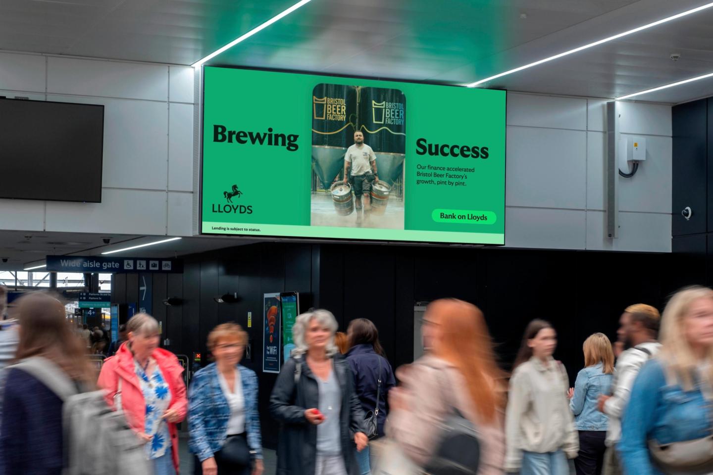 a digital billboard in a train station with an advertising campaign by Lloyd's Bank
