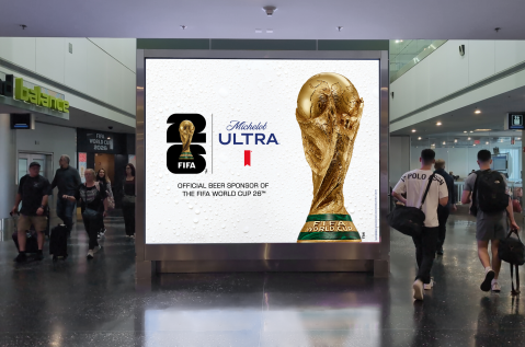 Travelers walk past large digital advertising for Michelob Ultra x FIFA World Cup in MIA