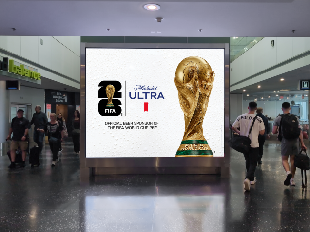 Travelers walk past large digital advertising for Michelob Ultra x FIFA World Cup in MIA