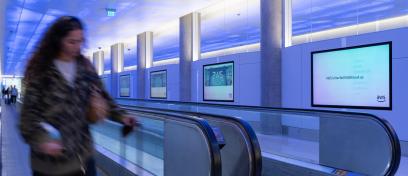 Passenger walks past Digital Brand Experience advertising for AWS at LAX