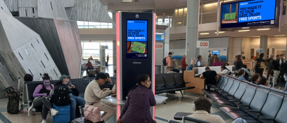 Passengers in DFW wait for their flights by two JCDecaux screens 