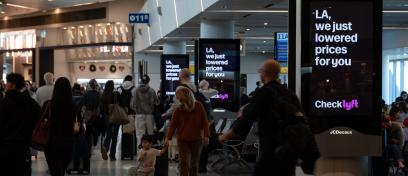 Passengers walk by synched digital screens advertising for Lyft in LAX