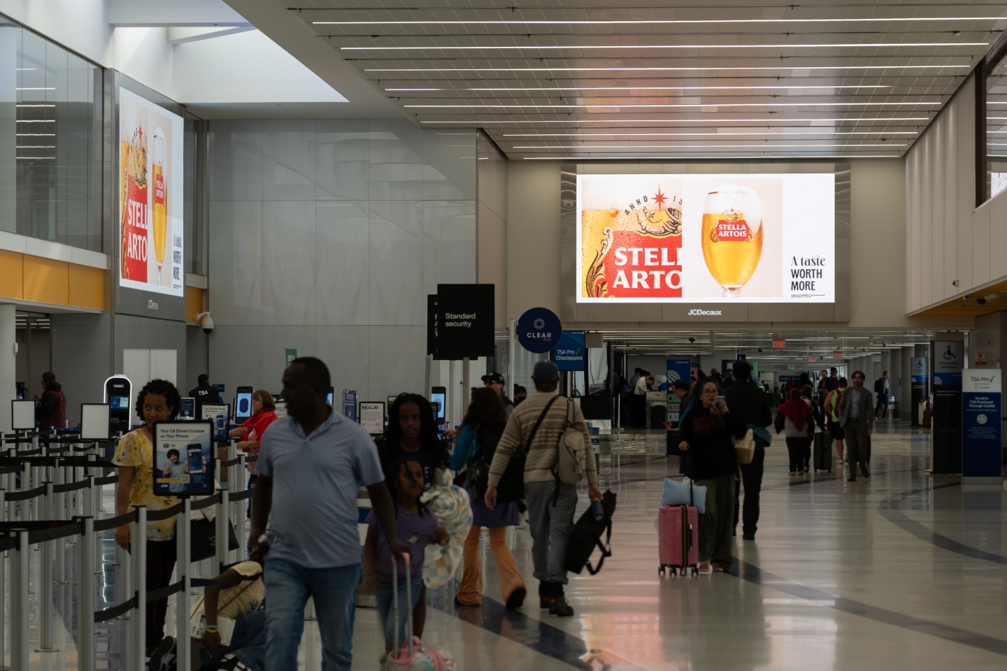 Massive overhead screens at LAX ticketing area display Stella Artois advertising