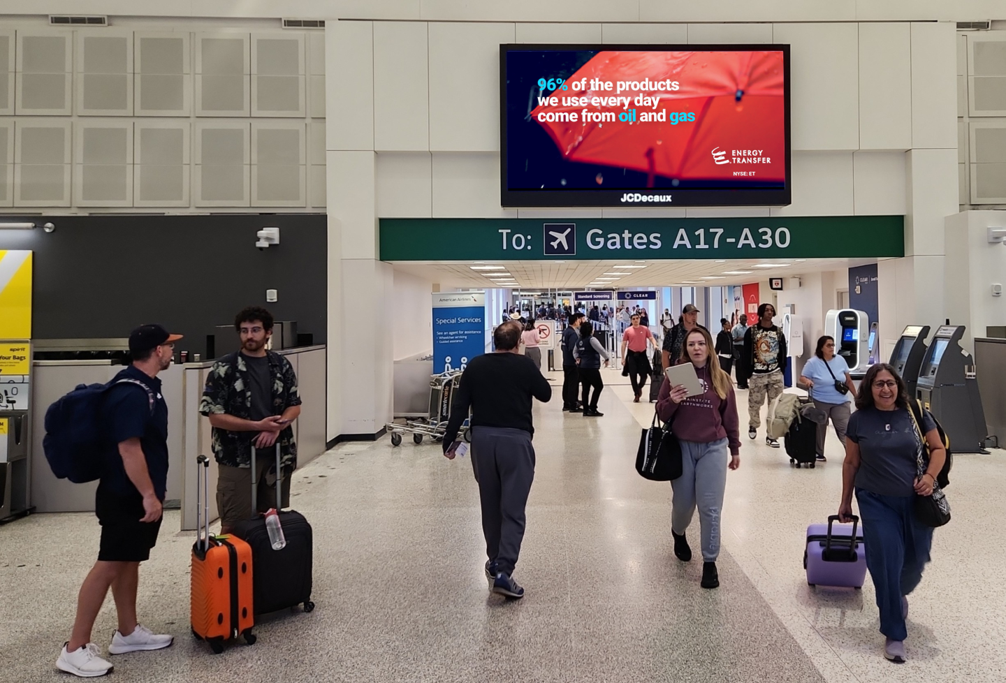Passengers walk under large format digital screen in IAH displaying Energy Transfer advertising