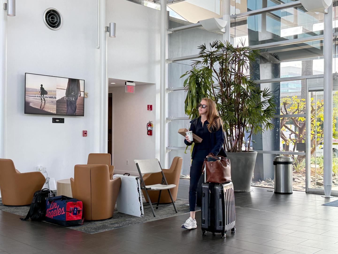 WOman walks through private aviation terminal in Los Angeles past screen showing IHG ad