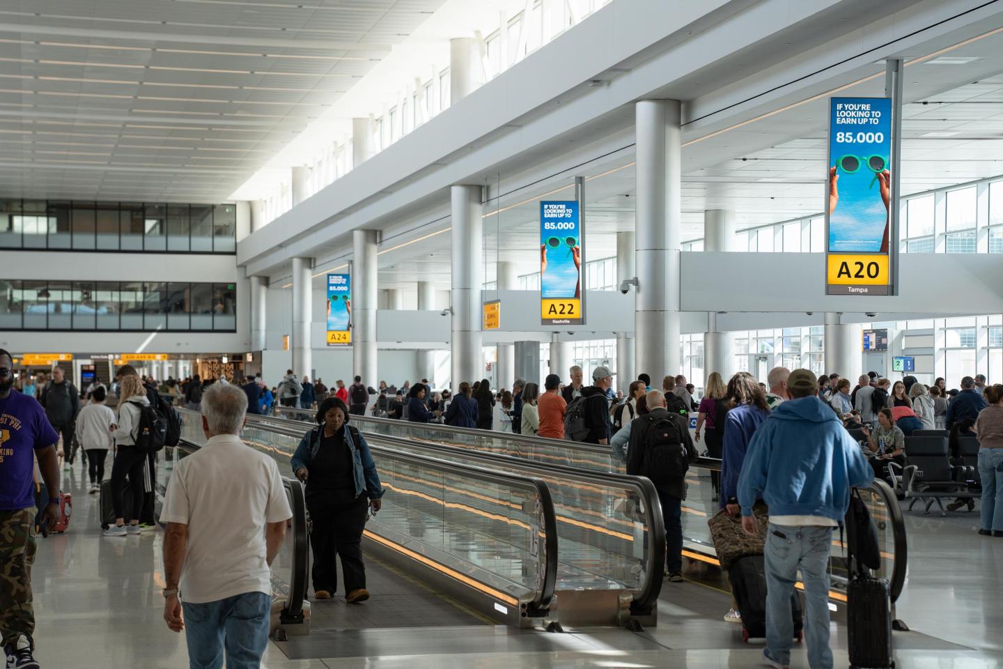 Passengers walk through DEN concourse next to synchronized digital networks