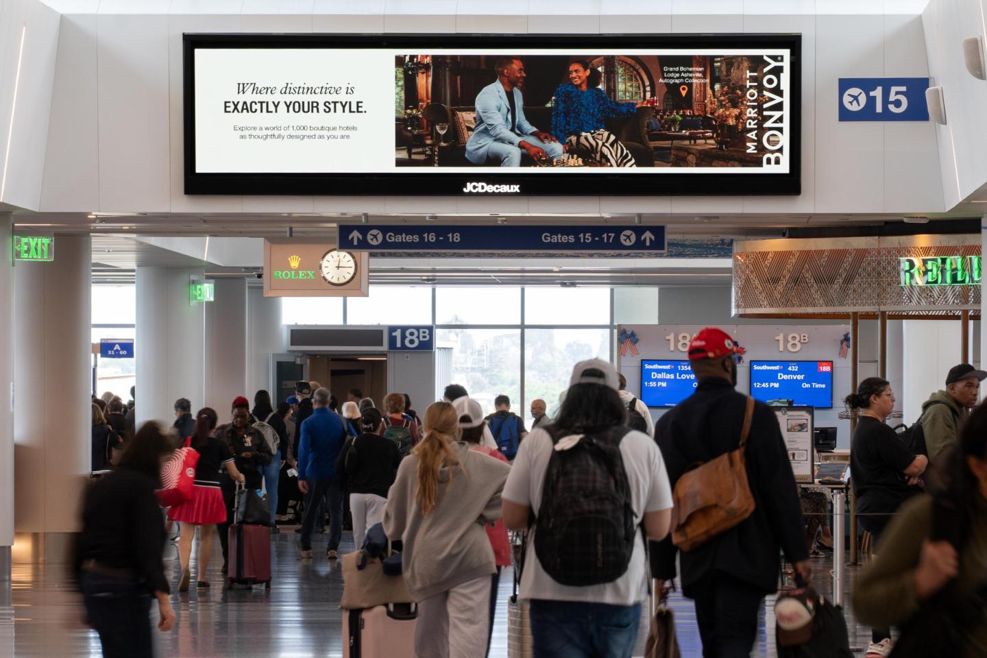 Passengers walk under large digital advertising screen in Los Angeles International Airport